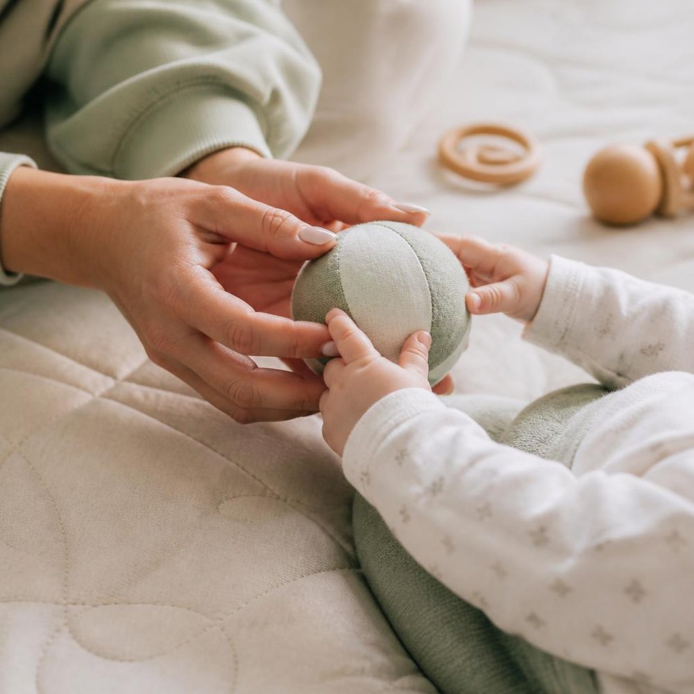 Mama reicht ihrem Baby einen weichen Ball
